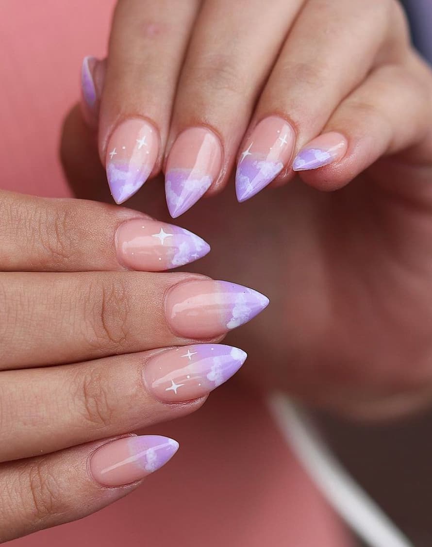 An image of a hand with light purple ombre on nude nails and cloud nail art