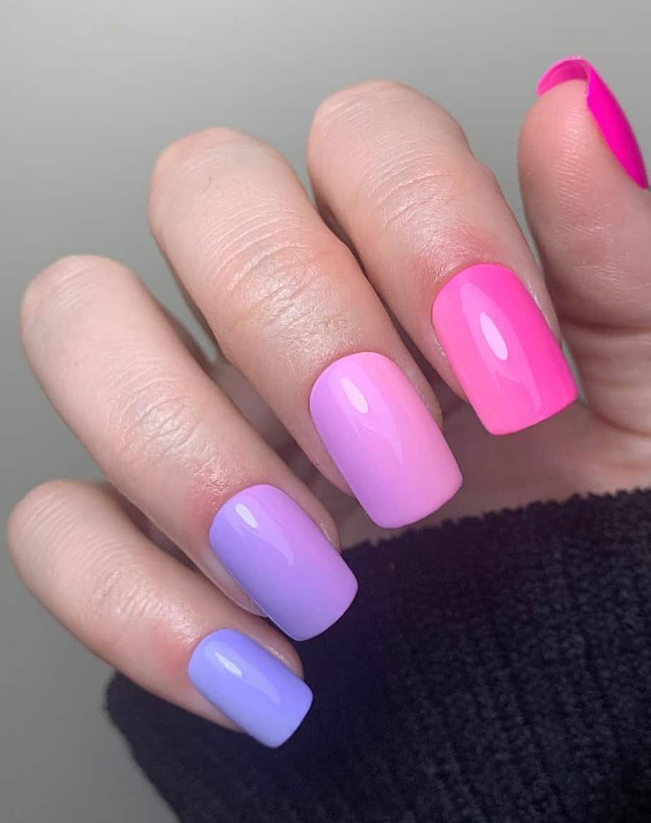 An image of a hand with square pink and purple ombre nails