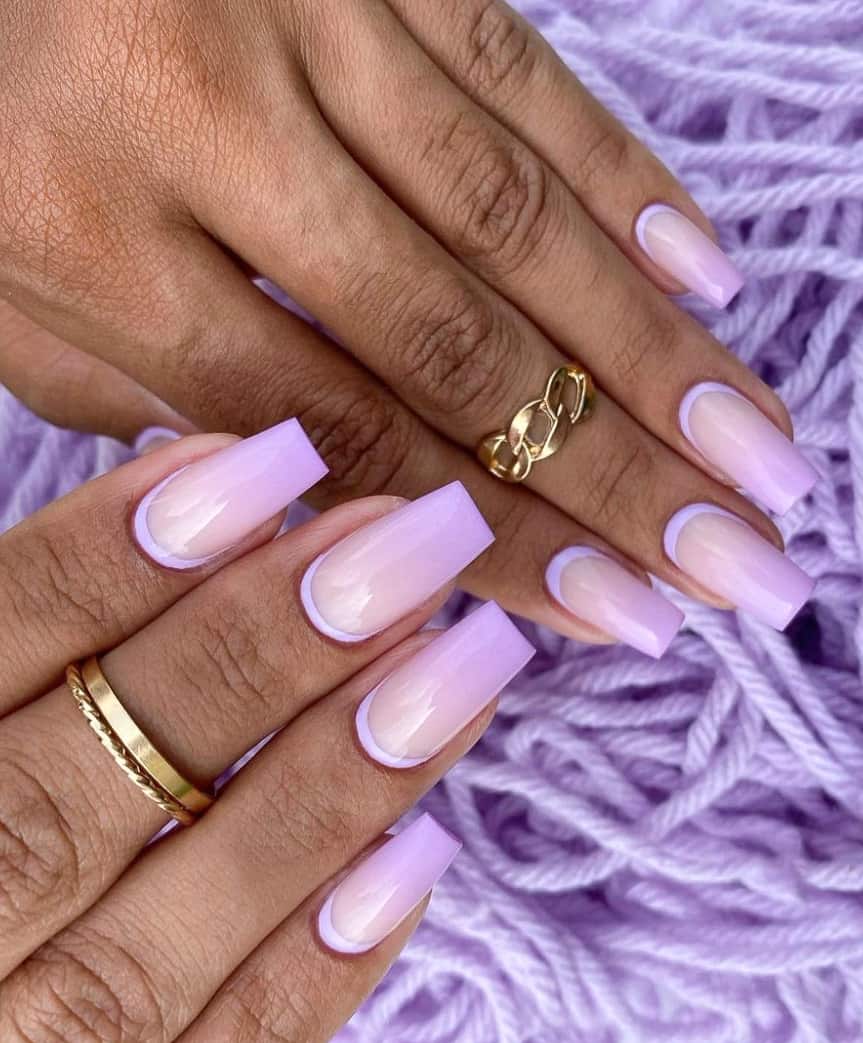 An image of a hand with lilac ombre nails and reverse French tips