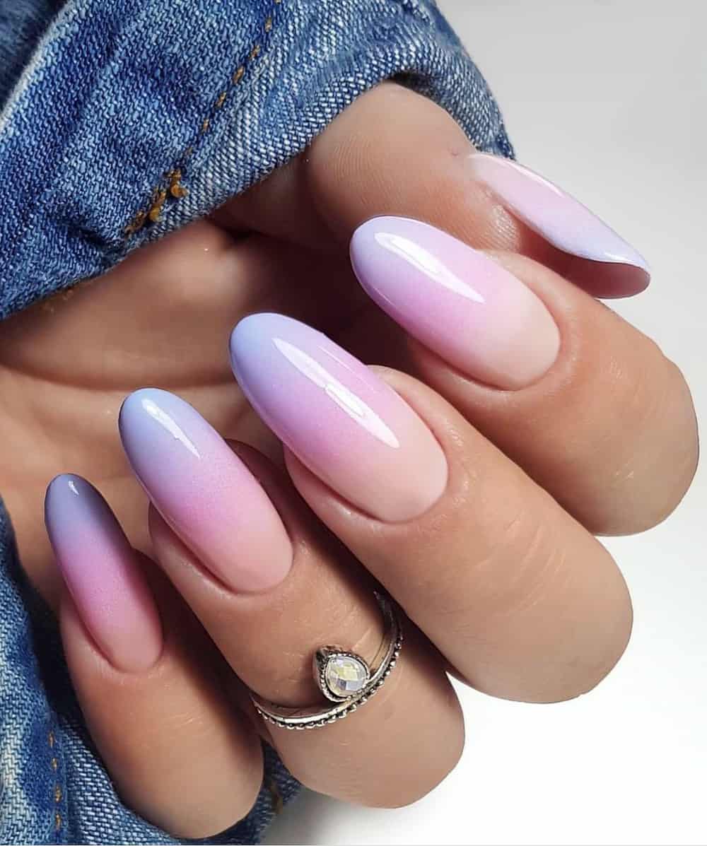 An image of a hand with rounded nails featuring purple to nude ombre