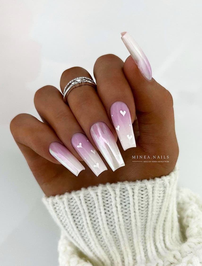 An image of a hand with long square nails with purple and white ombre and white heart accents