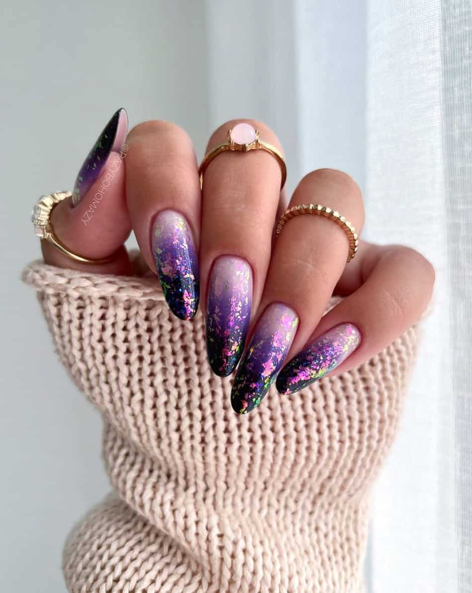 An image of a hand with long round nails featuring lilac purple polish and dark purple glitter ombre