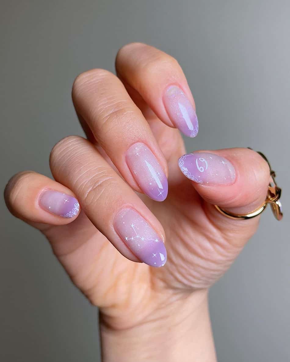 An image of a hand with nude and purple ombre featuring white constellation and astrology nail art