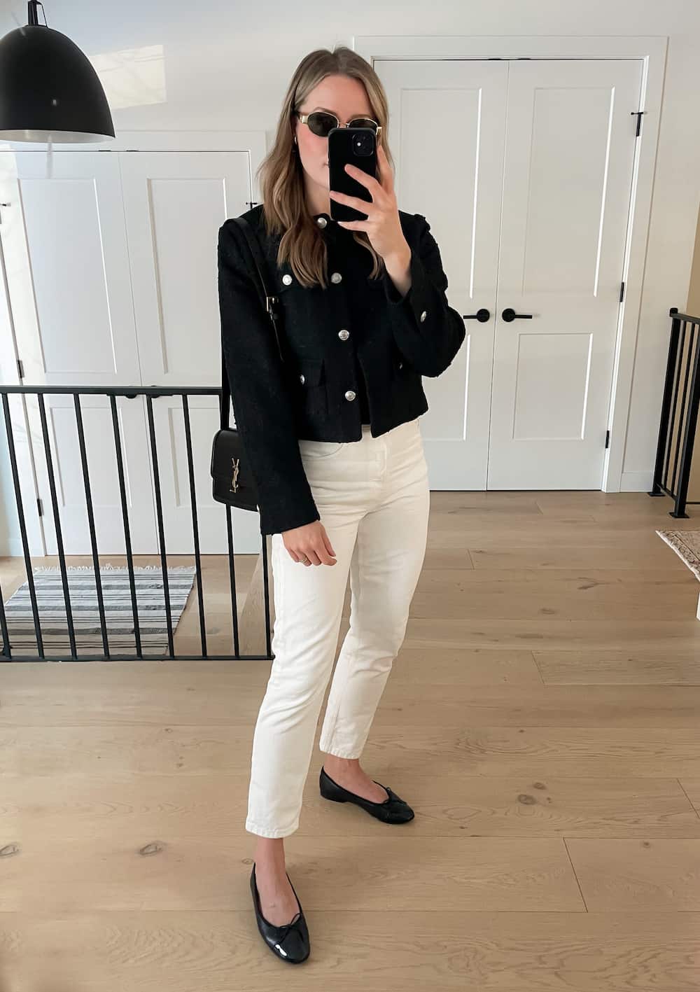 woman wearing a spring capsule wardrobe outfit with an black tweed lady jacket, black top, off-white jeans, and black ballet flats