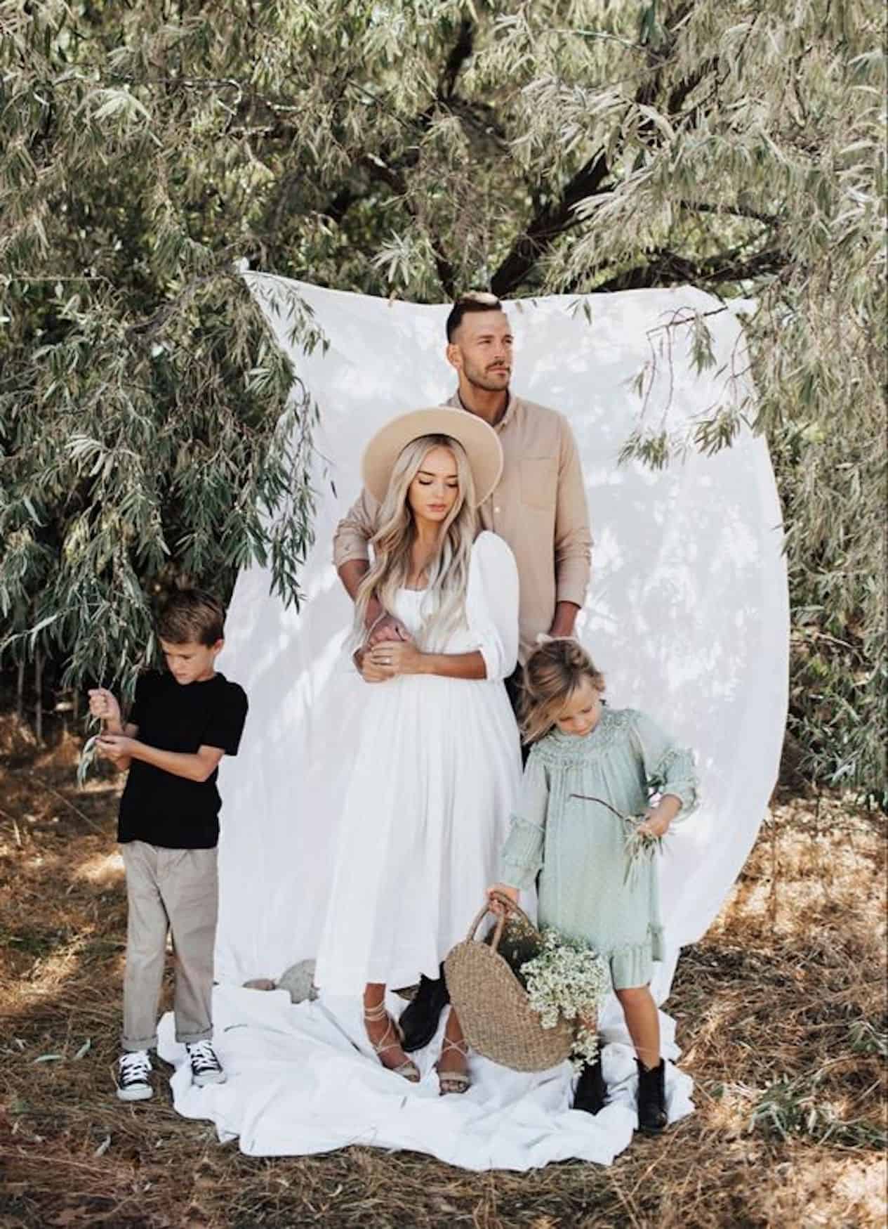 image of a family in a field with a tree in the background and a large white hanging sheet, wearing dressy clothing