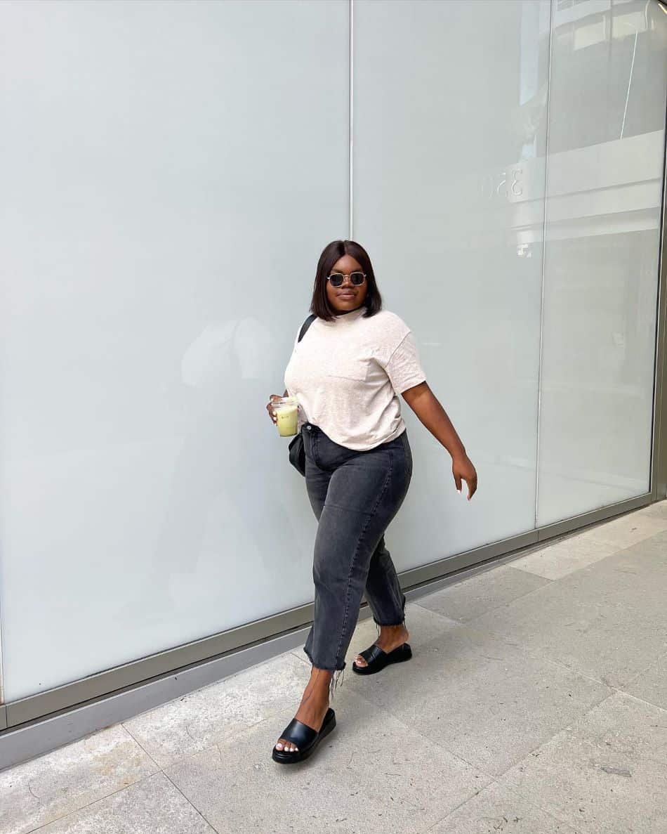 A woman wearing black jeans with a casual white top and black sandals