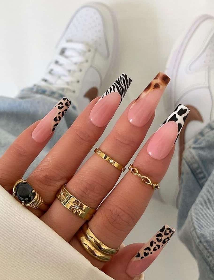 A hand with medium coffin nails featuring cheetah, zebra, giraffe, and cow print French tips