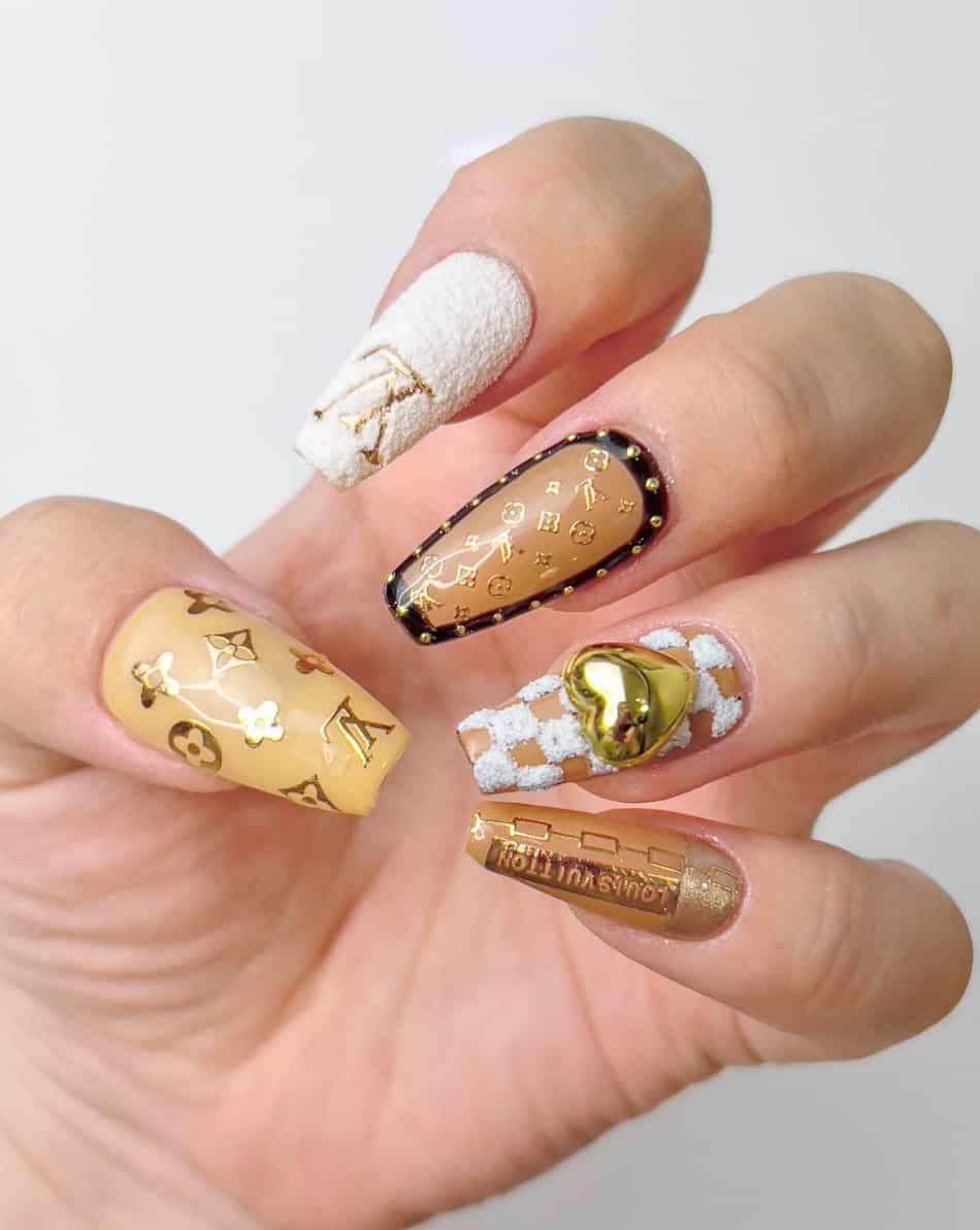 A hand with beige and white collage coffin nails with gold details and Louis Vuitton logos