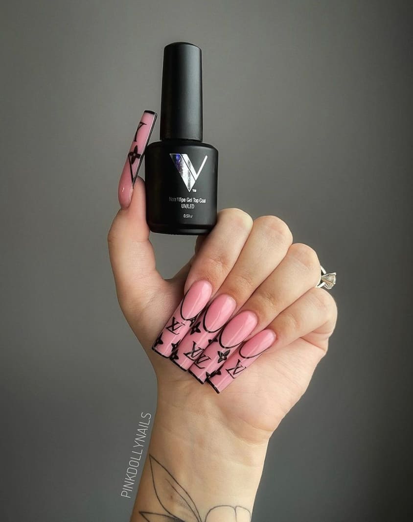 A hand with long square nails with pink polish and French tip outlines surrounding a Louis Vuitton logo