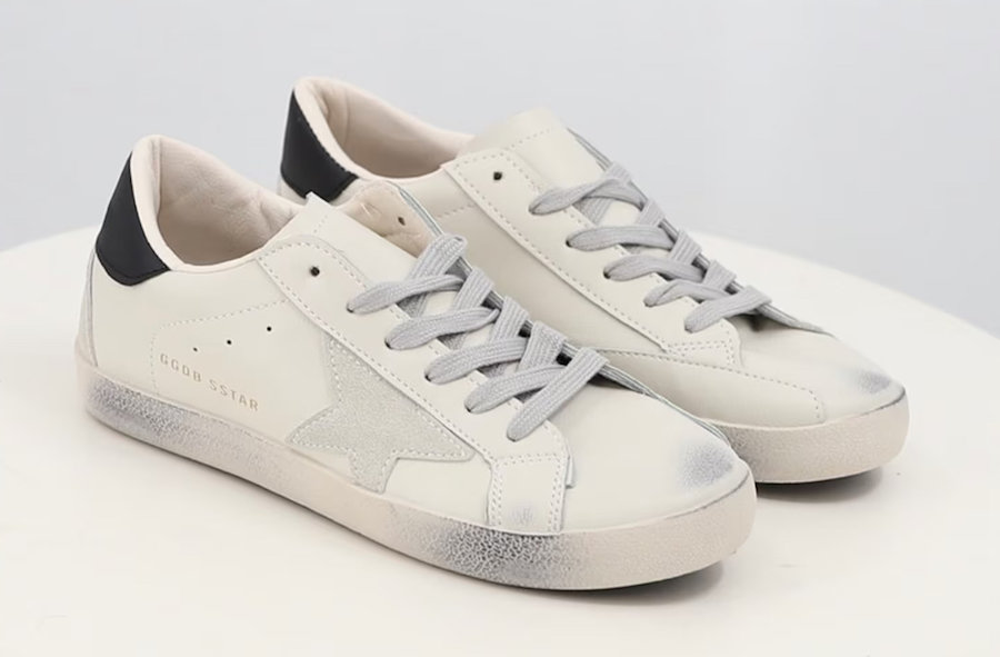 image of a pair of white sneakers with a star detail on the side and distressing