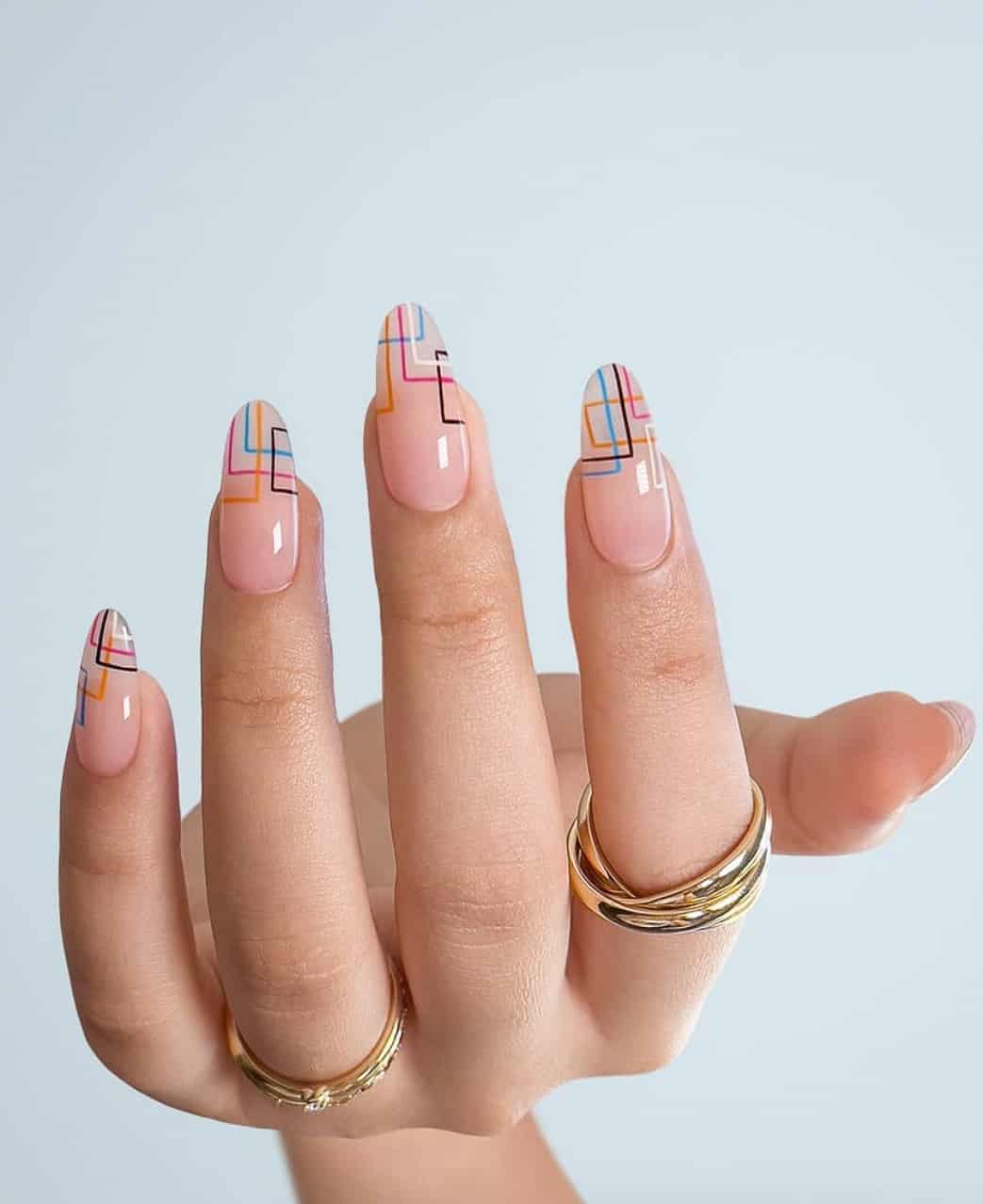 A hand with nude almond nails painted with colorful geometric lines