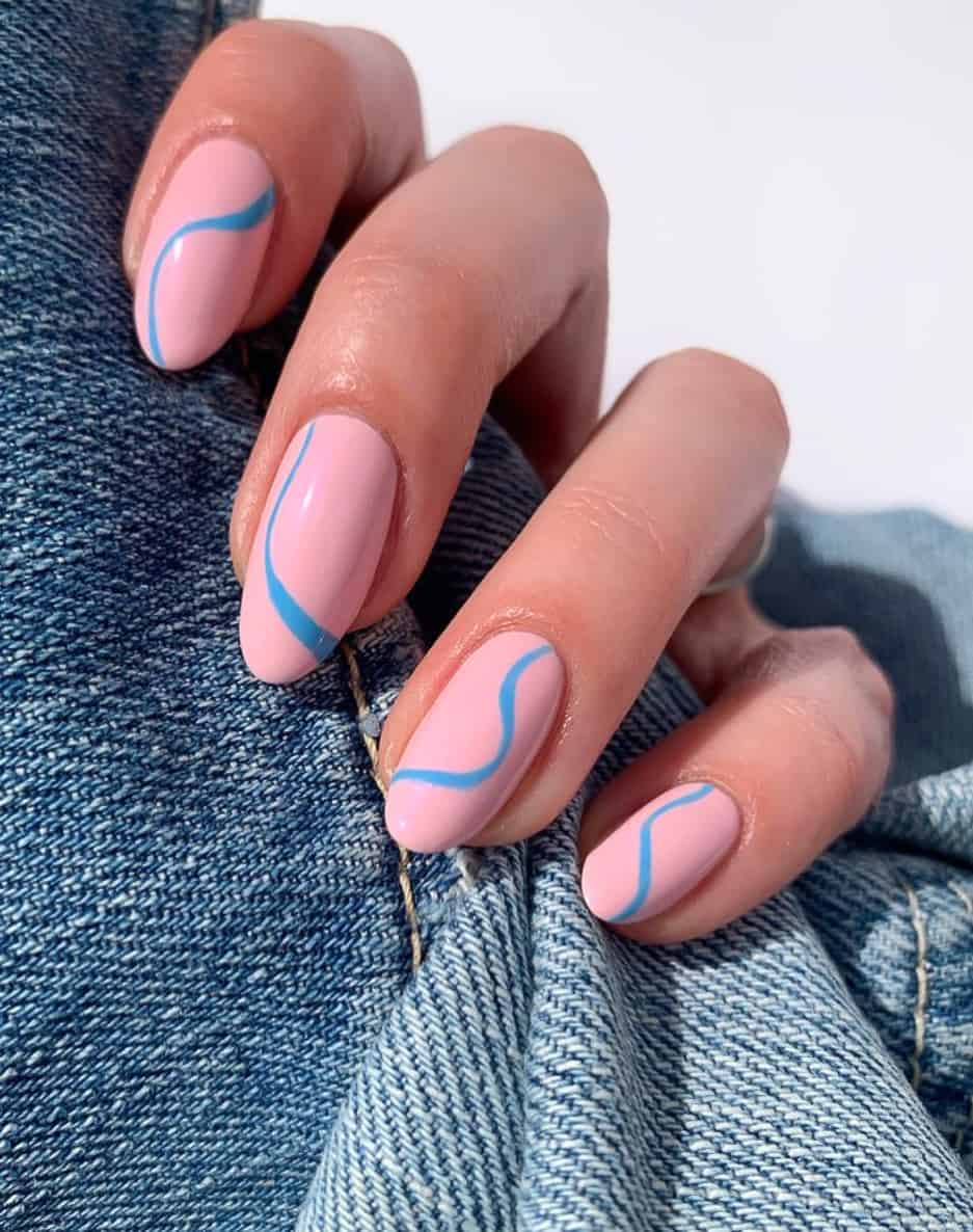 A hand with pastel pink almond nails and blue wave accents