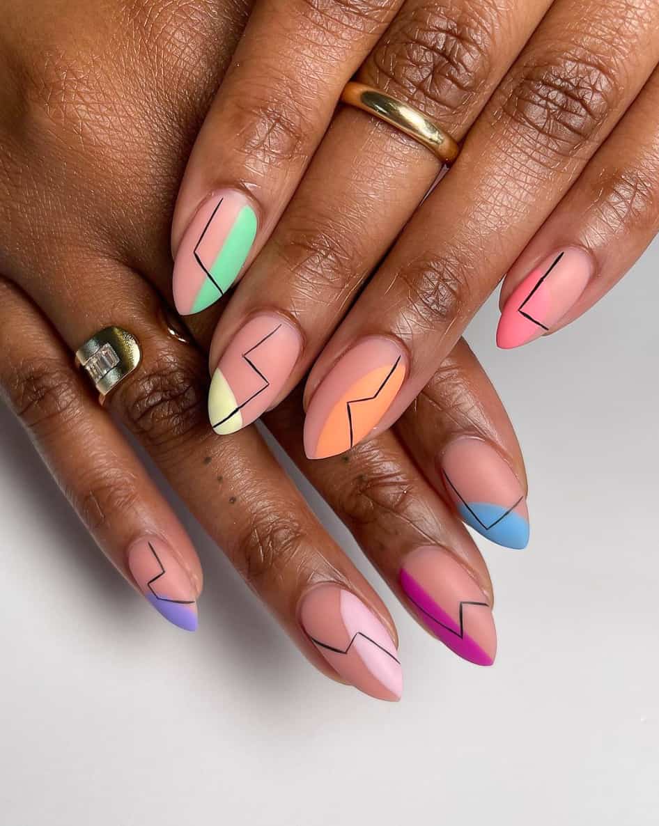 A hand with matte nude almond nails with colorful accents and black zig zag lines