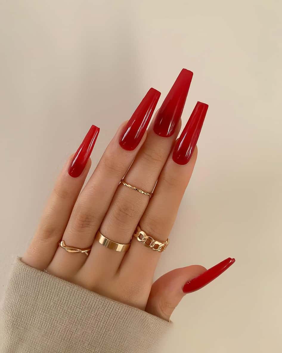 A hand with long coffin nails with translucent red polish