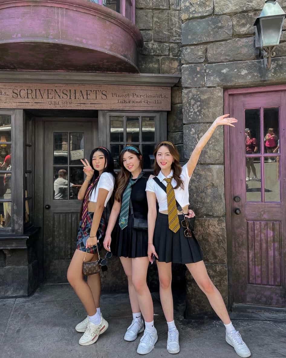 Three woman at Harry Potter World in Universal Studios, wearing Harry Potter-themed outfits with mini skirts, colored ties, and sneakers