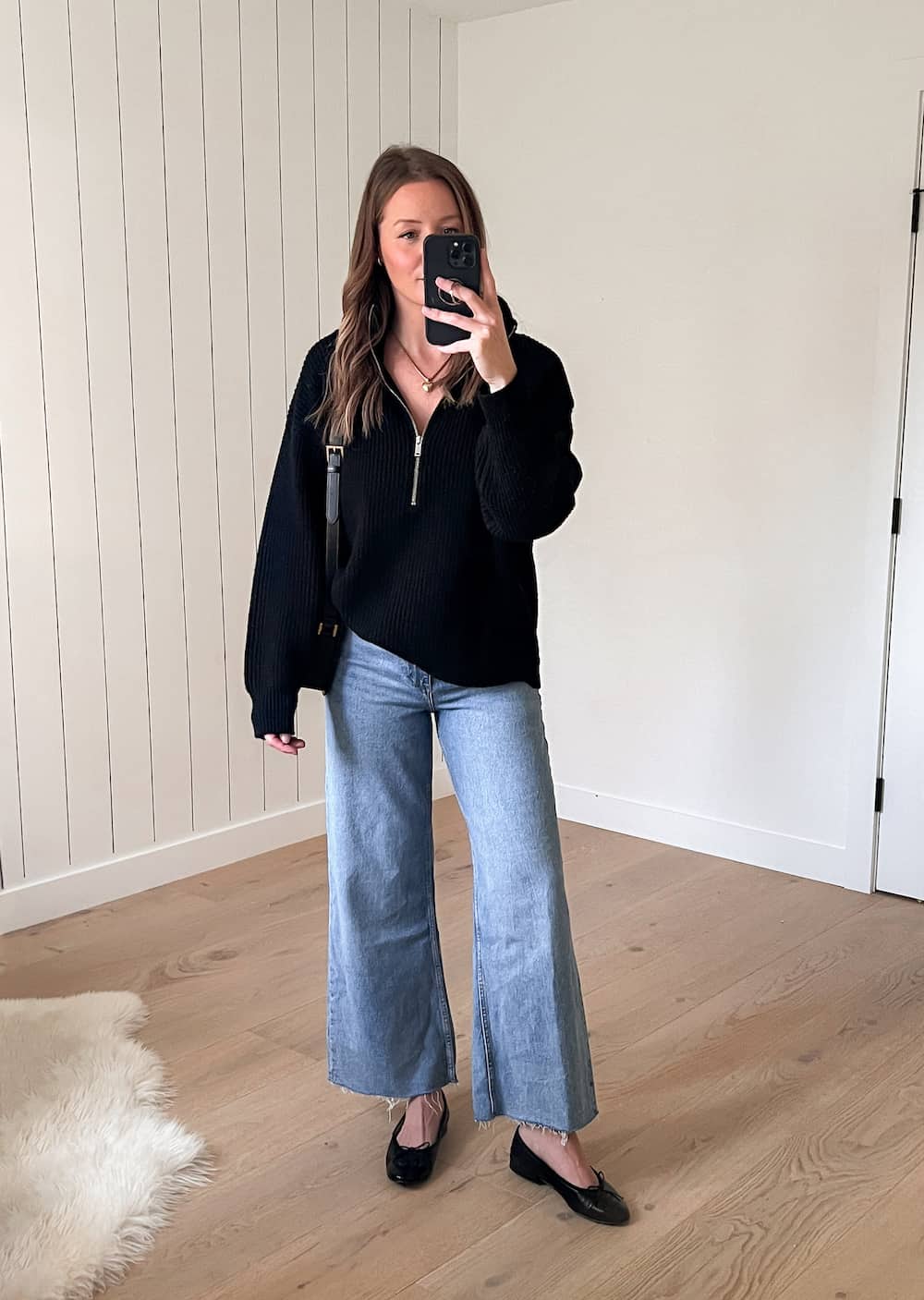Christal wearing an outfit with a black half-zip sweater and wide-leg jeans from Mango with black ballet flats as an idea for a capsule wardrobe outfit
