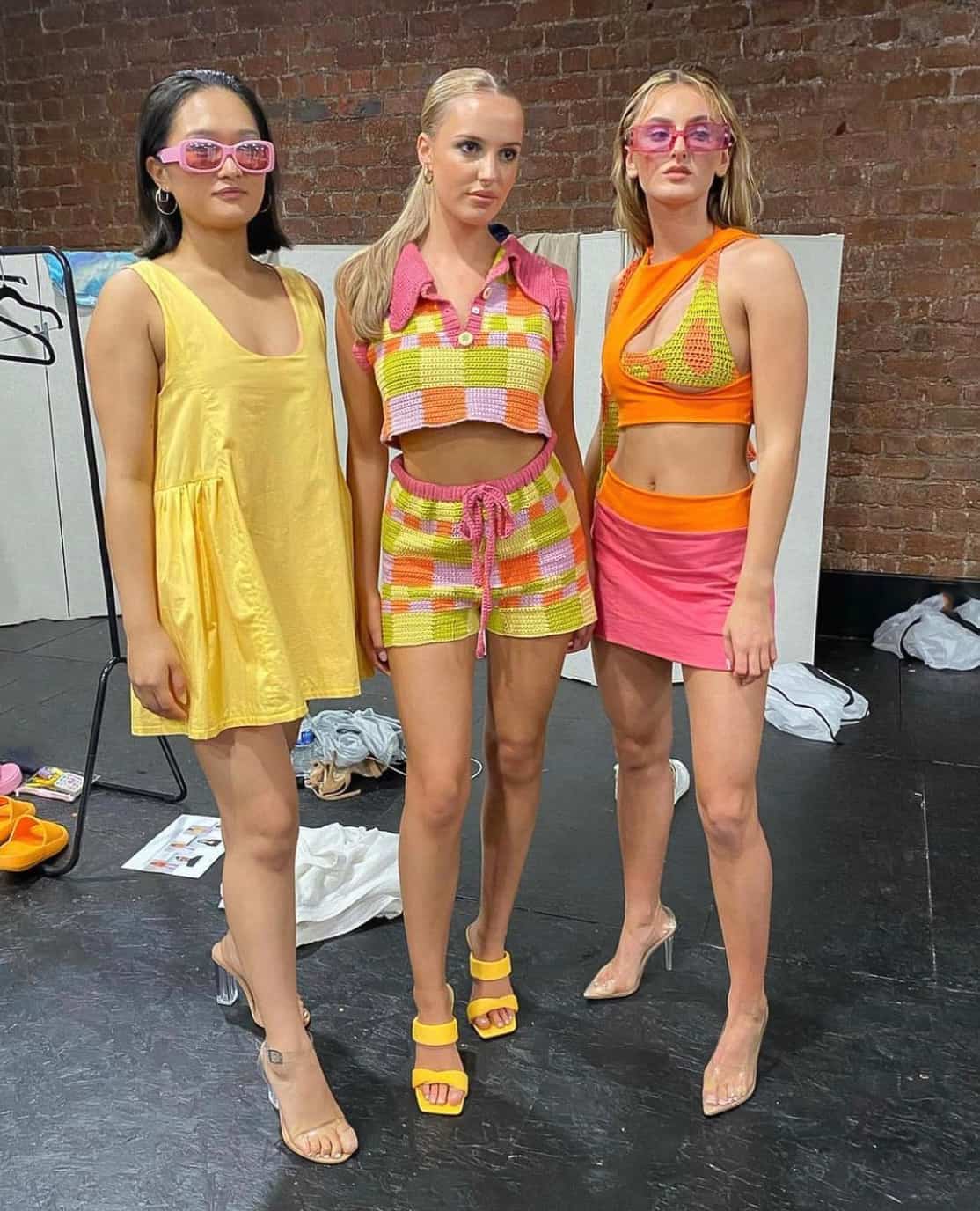 Three woman wearing Harry Styles concert outfits featuring 70s inspired outfits that are yellow, orange, and pink