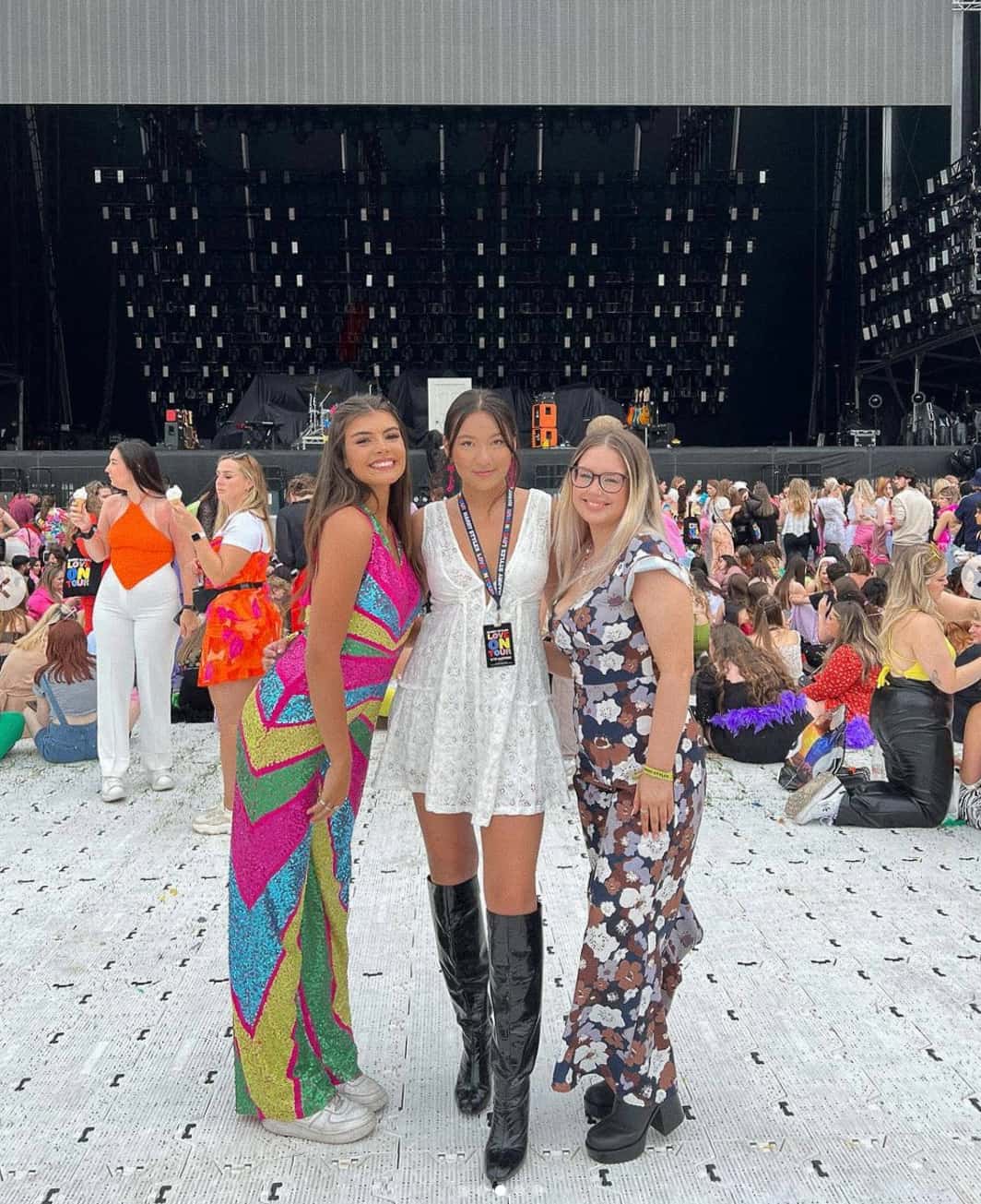 Three woman standing together with Harry Styles concert outfits