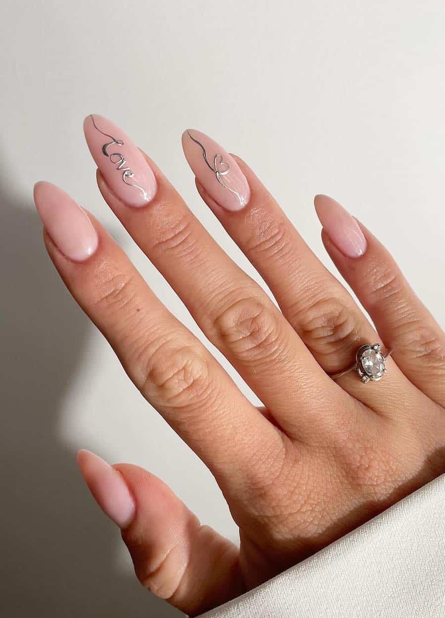 image of a hand with almond nude pink nails with silver "love" text in cursive
