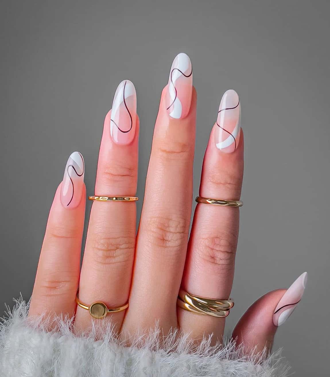 A hand with long nude almond nails featuring thick white wavy lines and thin black wavy lines