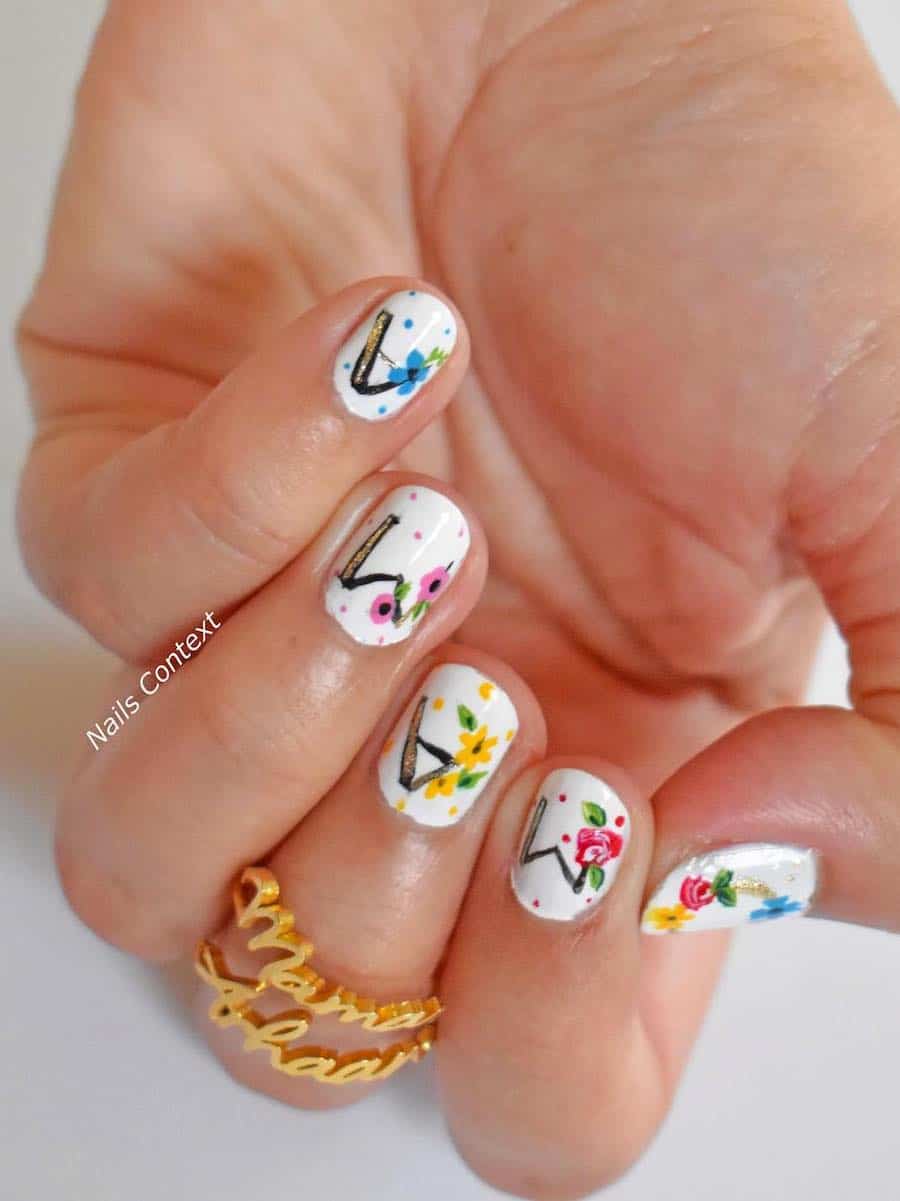 image of a hand with white nail polish and floral art with the word MAMA on the nails
