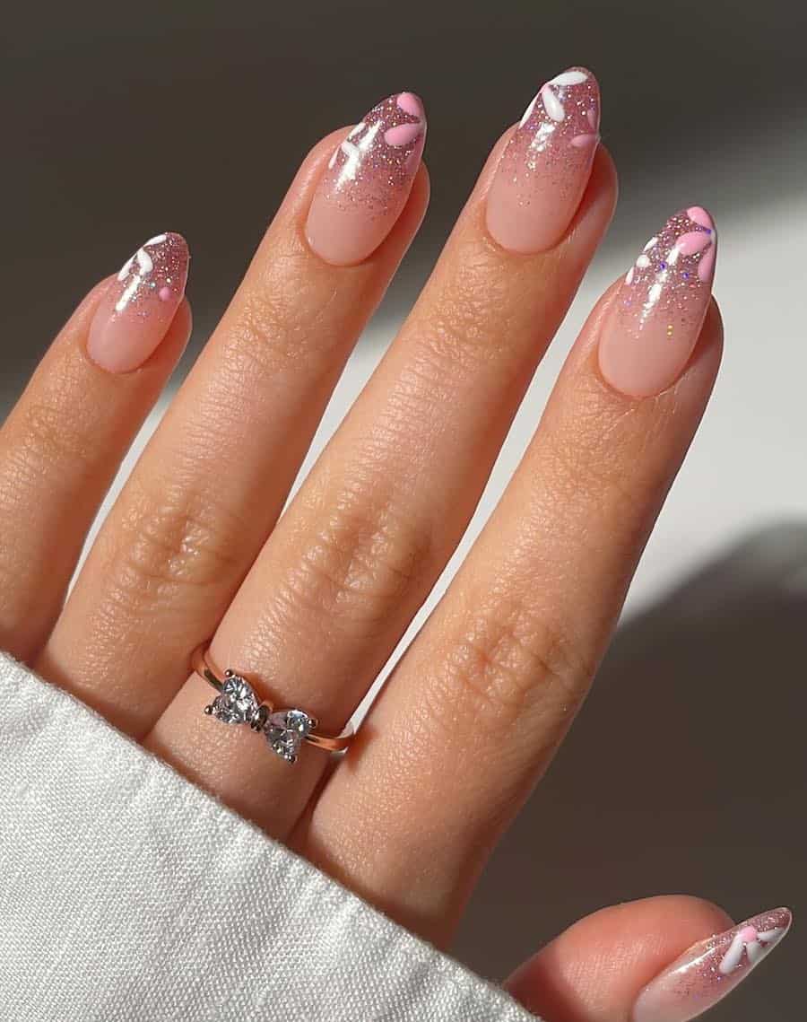 image of a hand with pink floral nail art and glitter french tips