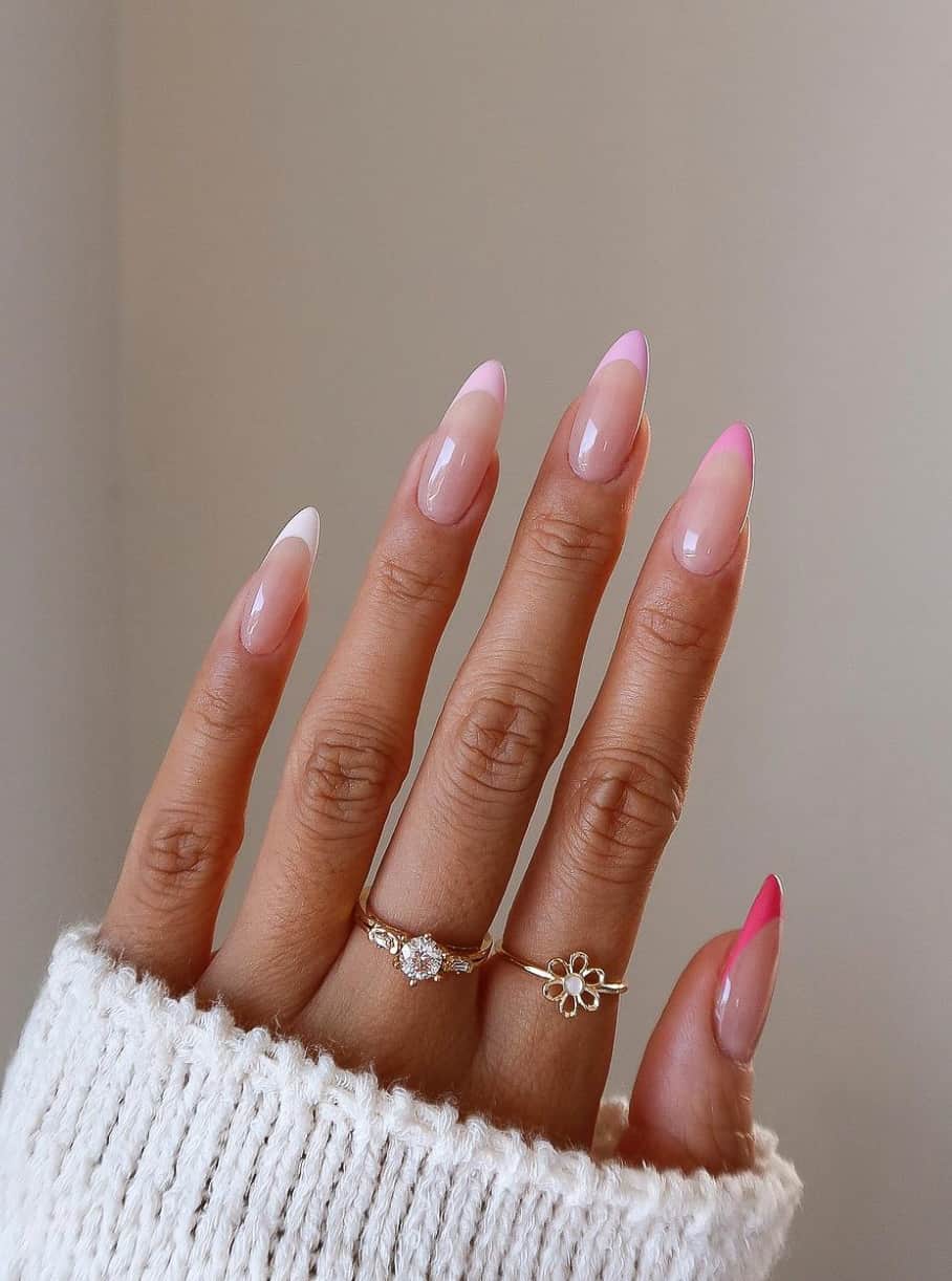 A hand with medium length almond nails featuring gradient pink to white French tips