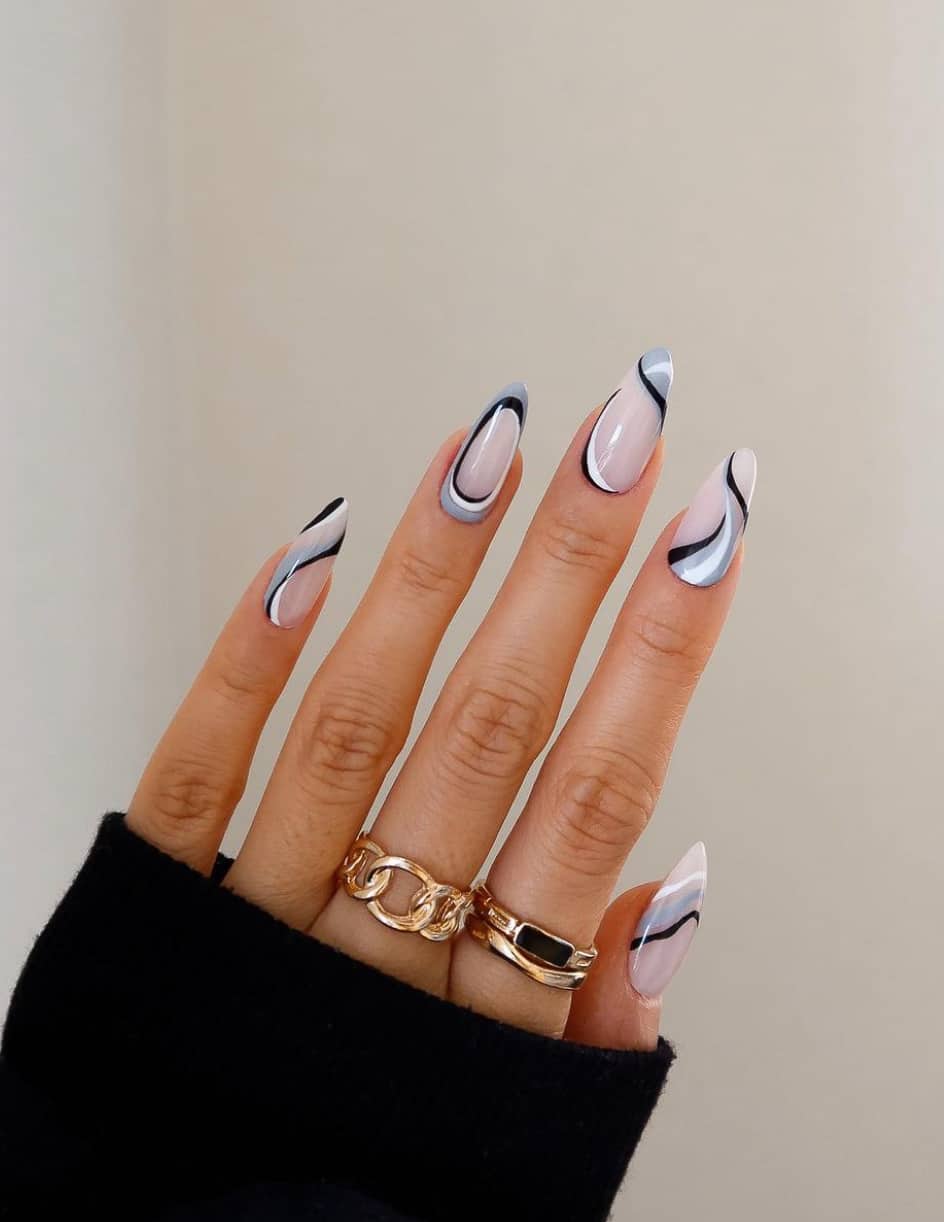 A hand with long almond nails featuring a milky white base and accented with white, grey, and black swirls