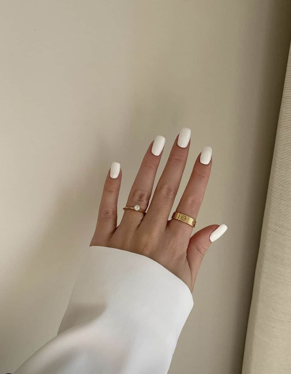 A hand with short solid white square nails