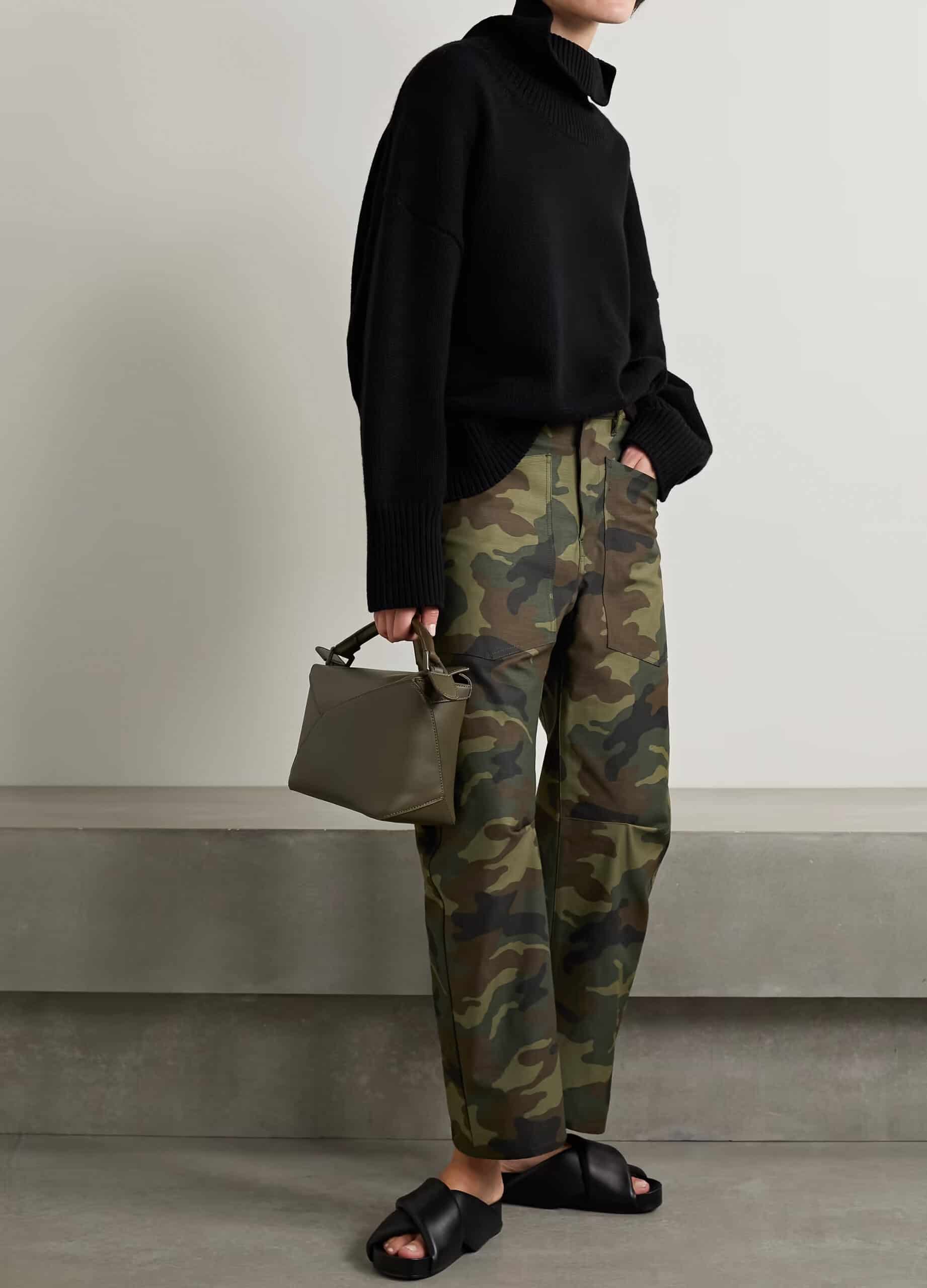 A woman wearing camo pants with a black turtleneck sweater and black slide sandals