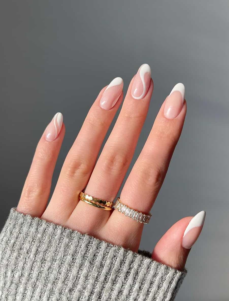 A hand with medium length nude nails with white French tips and white swirls