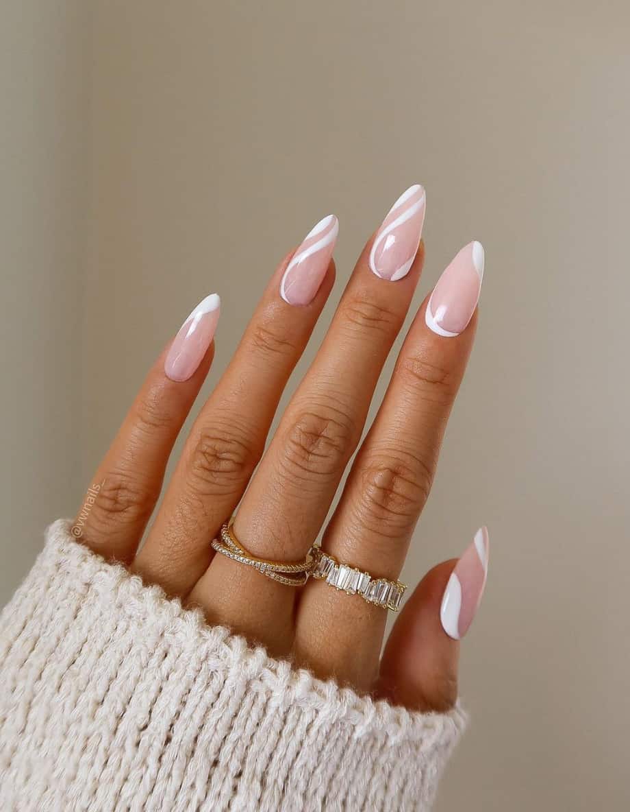 A hand with long nude pink almond nails featuring white swirls