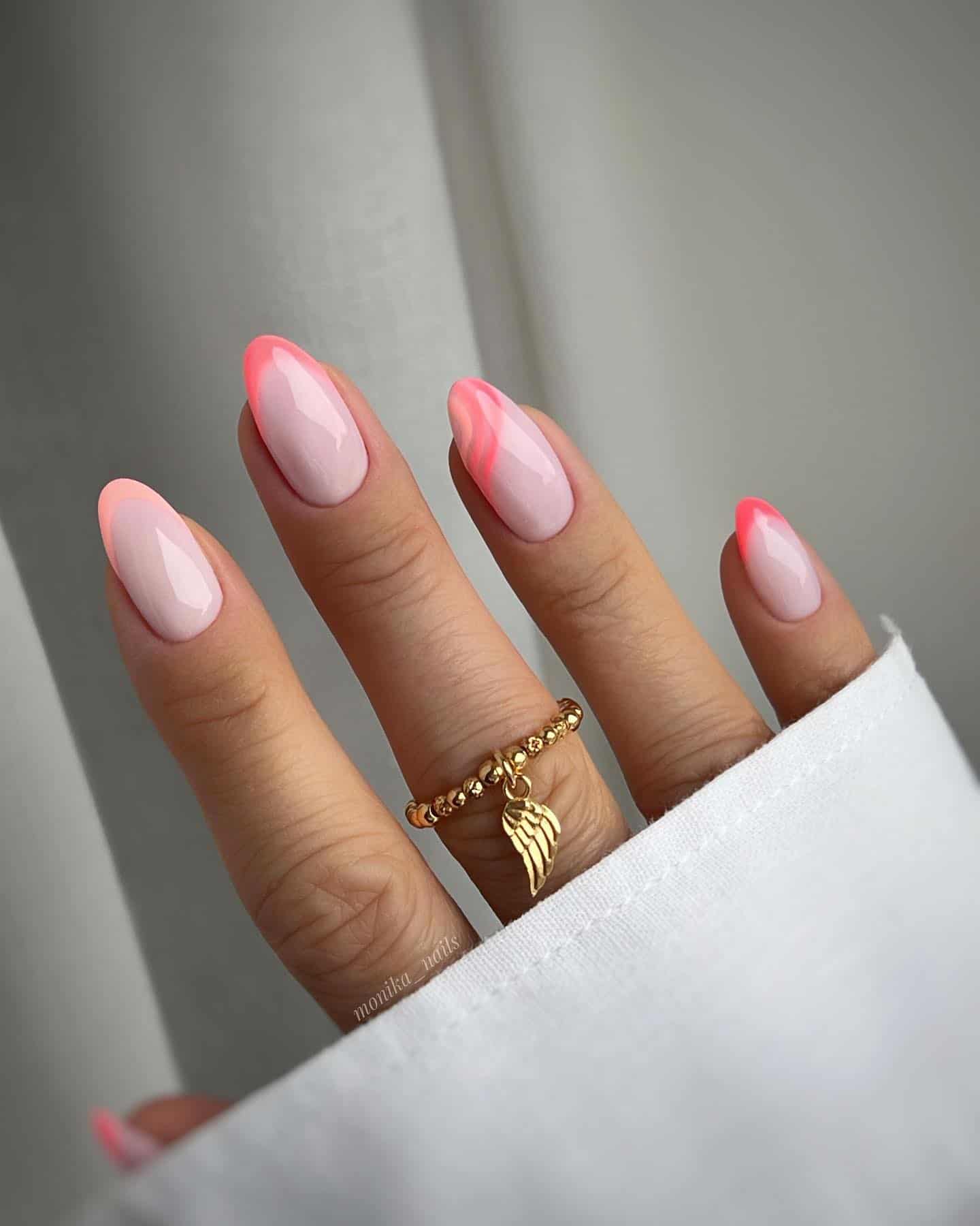 A hand with short almond nails painted a milky white color with peach and coral peach French tips and a wave accent nail