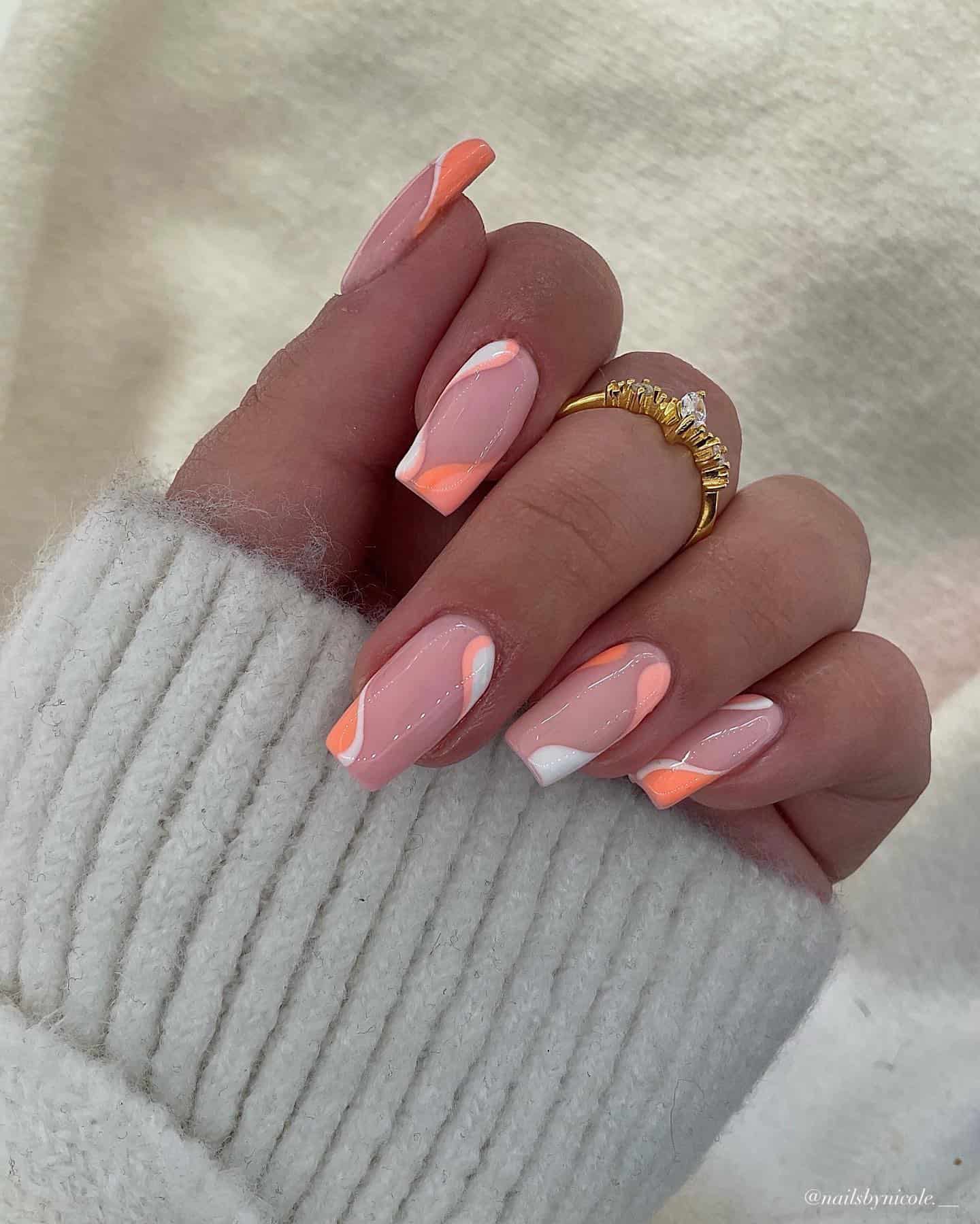 A hand with square nude pink nails painted in peach, coral peach, and white waves
