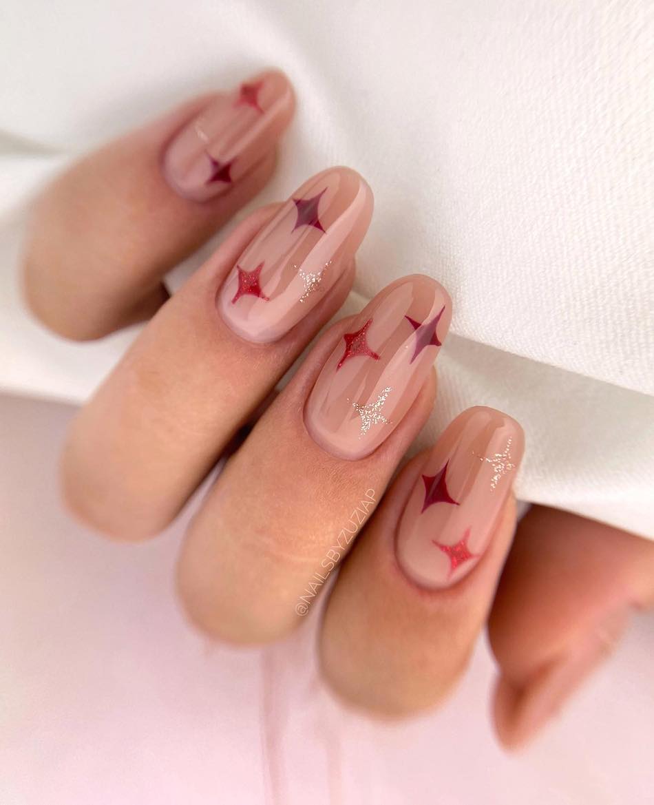 A hand with medium nude almond nails with red, dark red, and silver sparkles