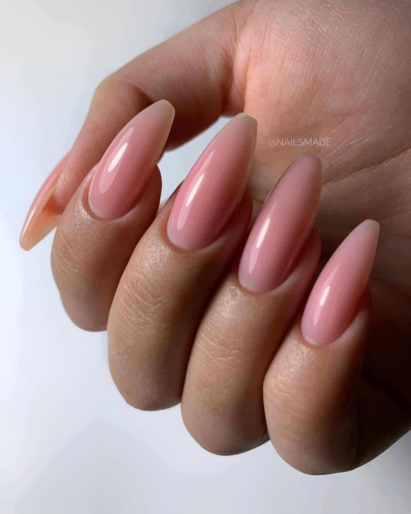 A hand with long coffin nails painted a glossy nude pink
