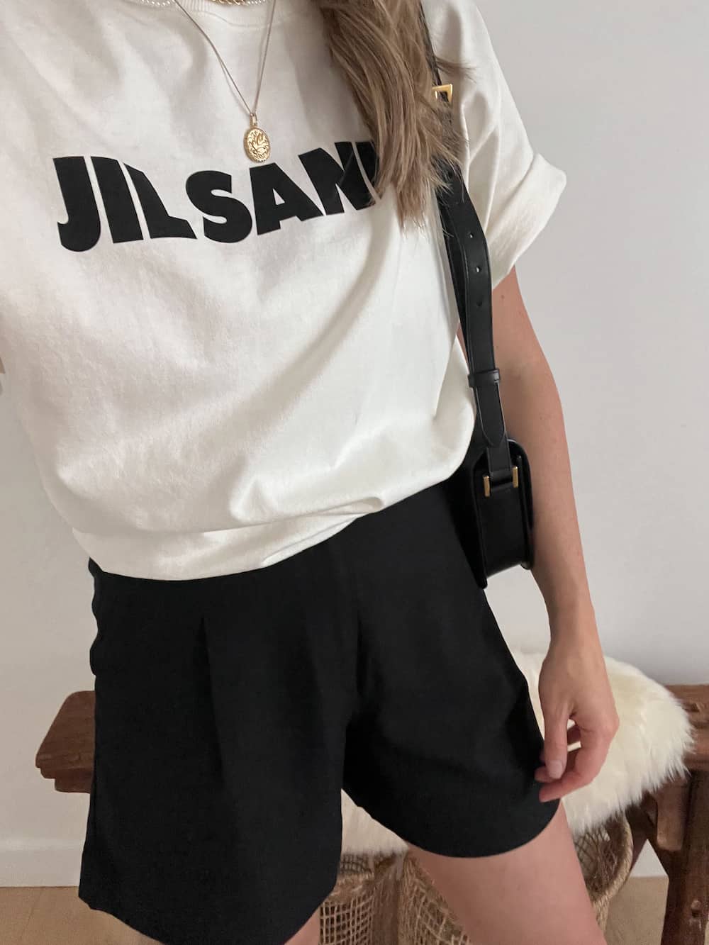 Woman wearing a white Jil Sander t-shirt with black linen shorts