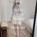 woman wearing a blue button down shirt with a brown belt and white linen shorts and brown sandals with text overlay "how to style linen shorts for summer"