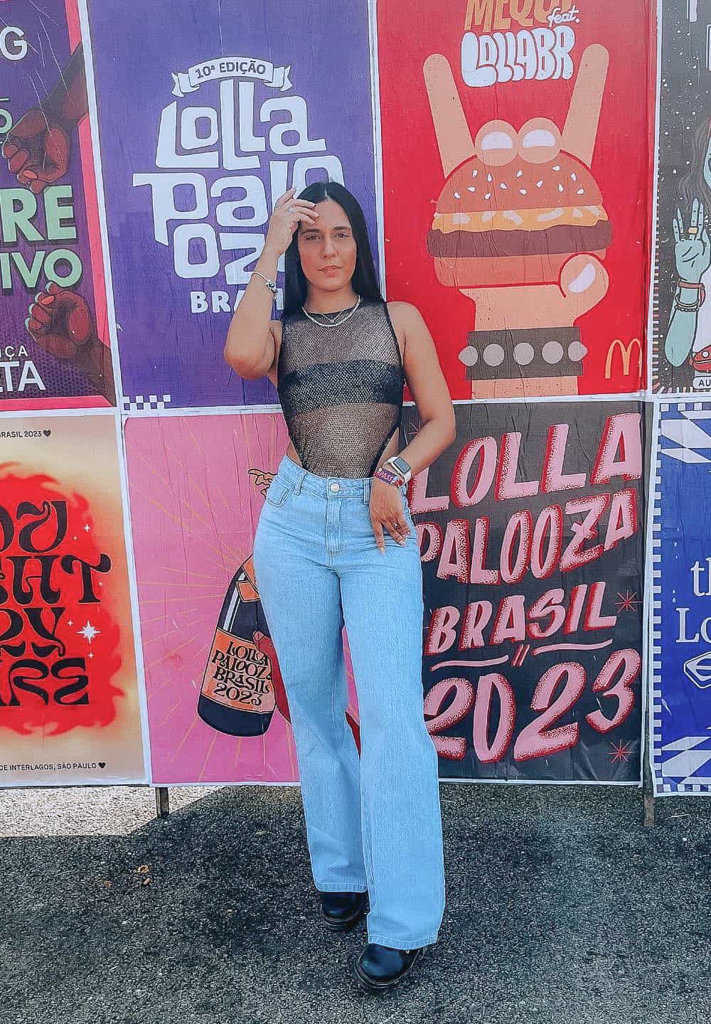 A woman at Lollapalooza wearing light washed flared jeans with a black bandeau top and a mesh tank