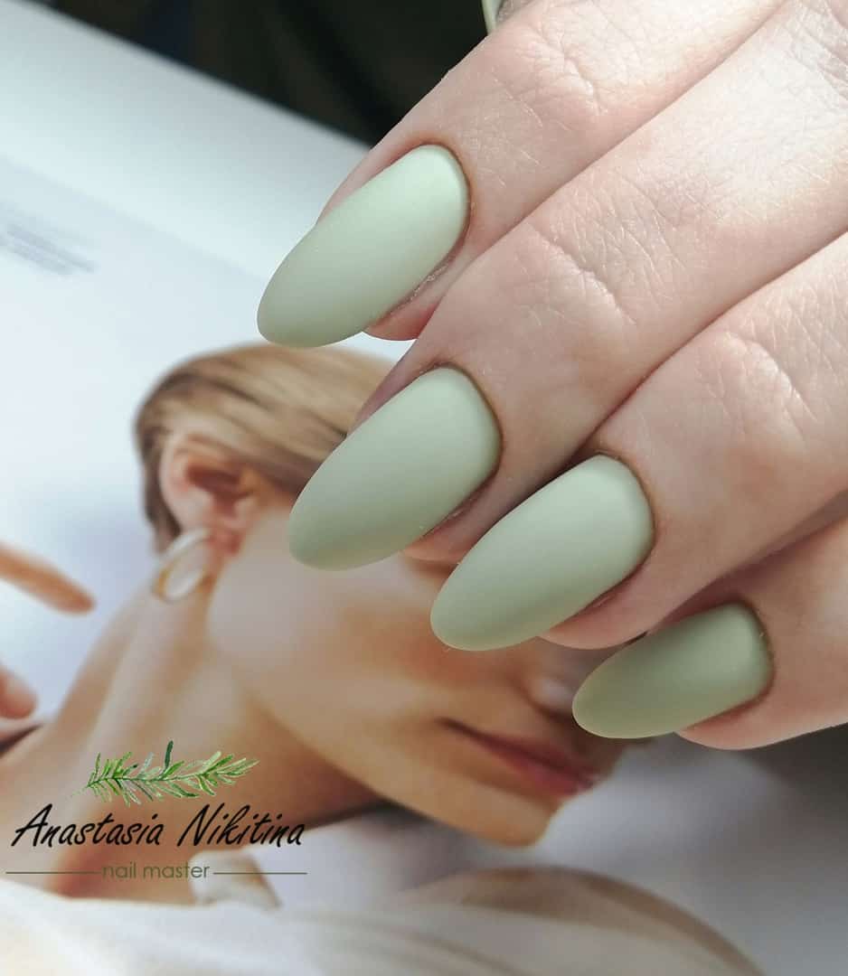 A hand with matte mint green almond nails