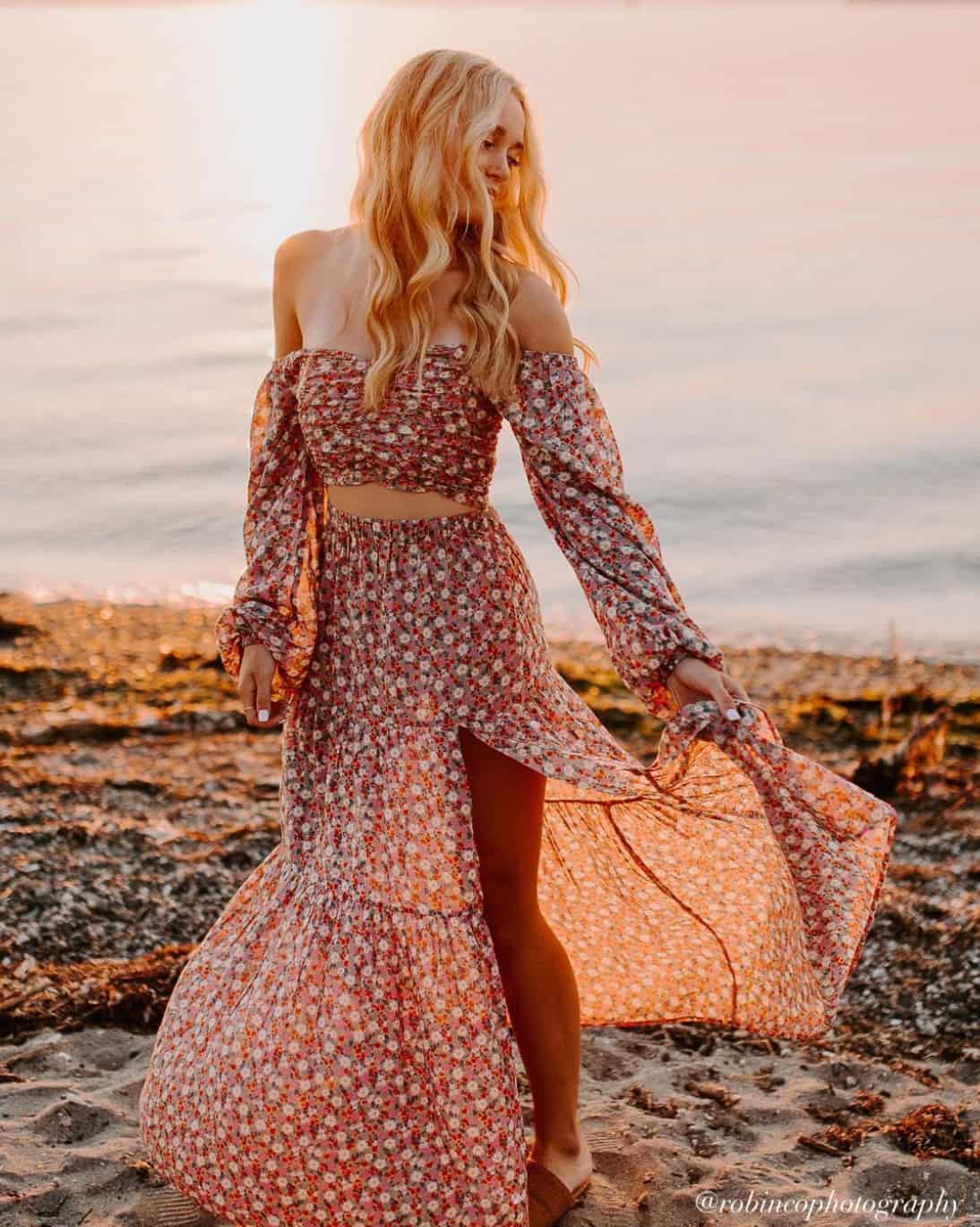 young woman wearing a matching floral blouse and midi skirt set at the beach for senior pictures