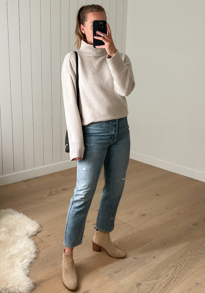 woman wearing a beige turtleneck with straight leg jeans and tan heeled chelsea boots
