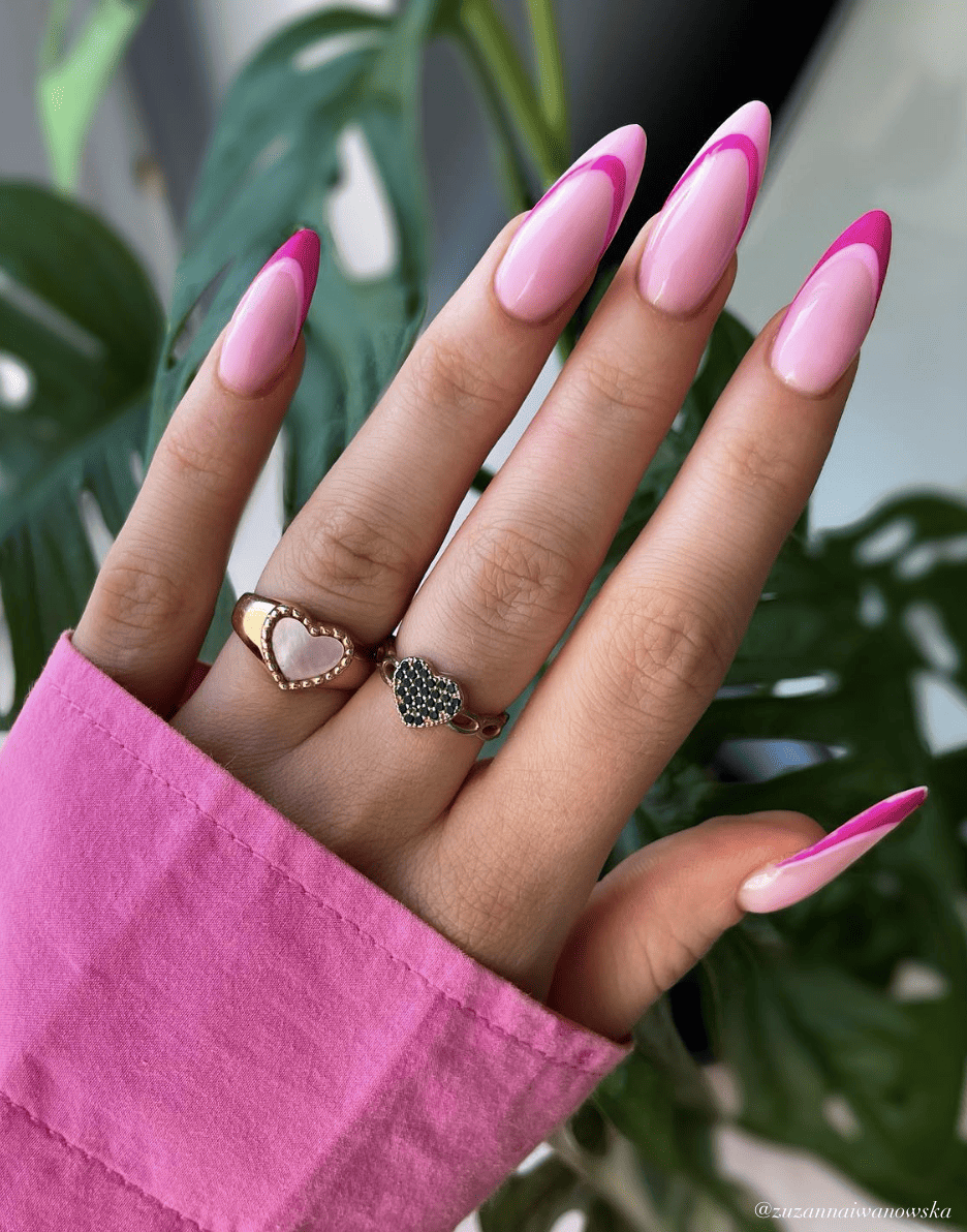 A hand with long almond nails painted a pastel pink with light pink and magenta French tips