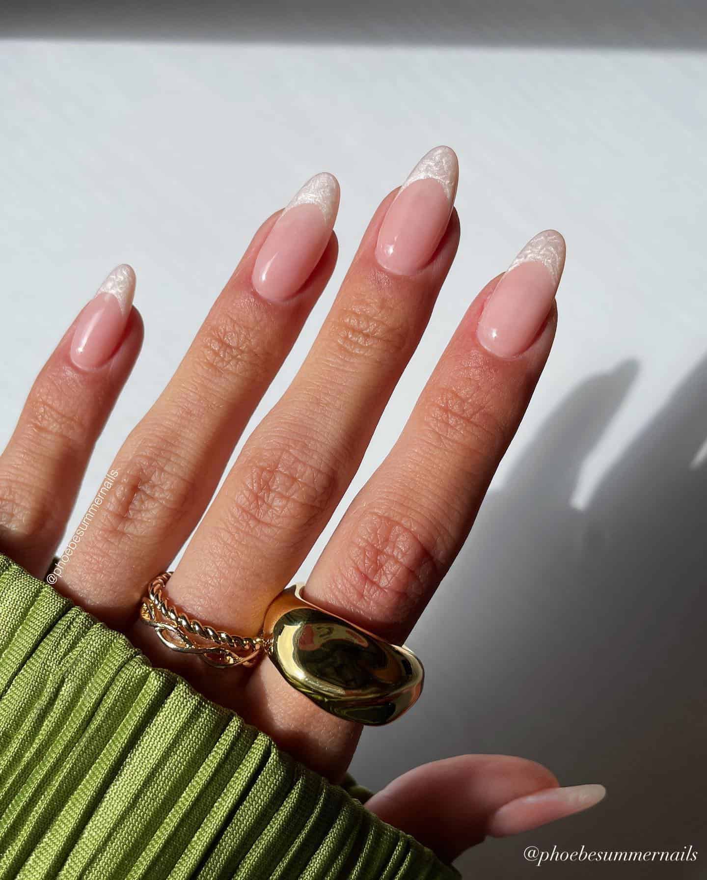 A hand with medium almond nails with shimmering pearly white French tips