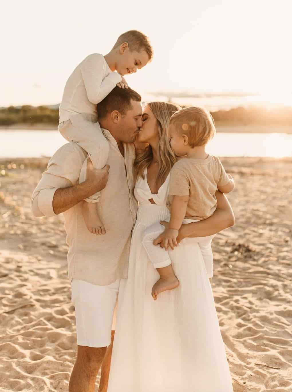 a family portrait with the mother wearing a white dress, the father wearing a beige button-up and white shorts, while the children are wearing white and beige bottoms and tops