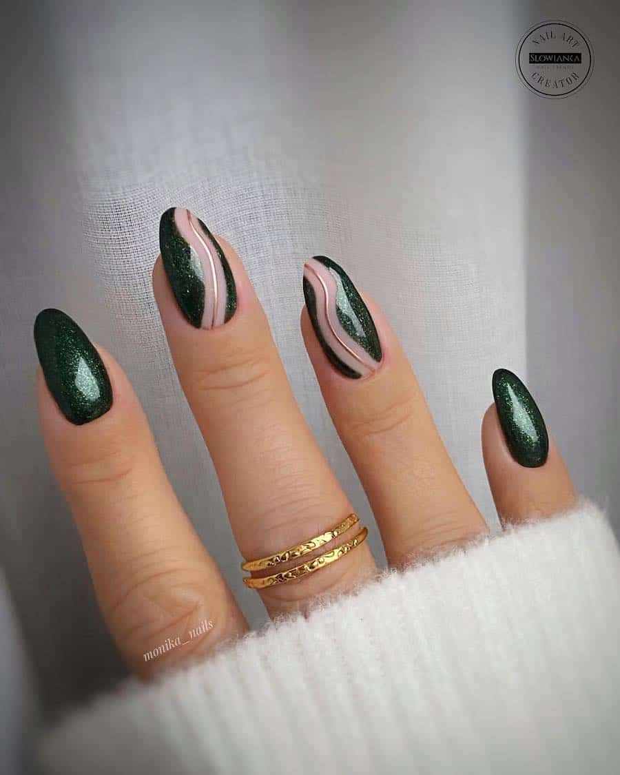 a hand with medium almond nails painted in a sparkly forest green shade with nude and gold wave accents