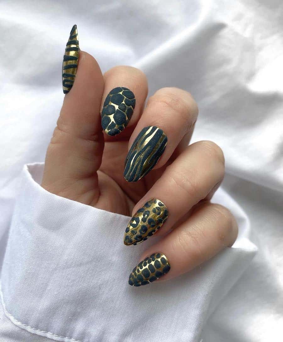 a hand with medium almond nails painted in gold and forest green with different animal print patterns on each nail