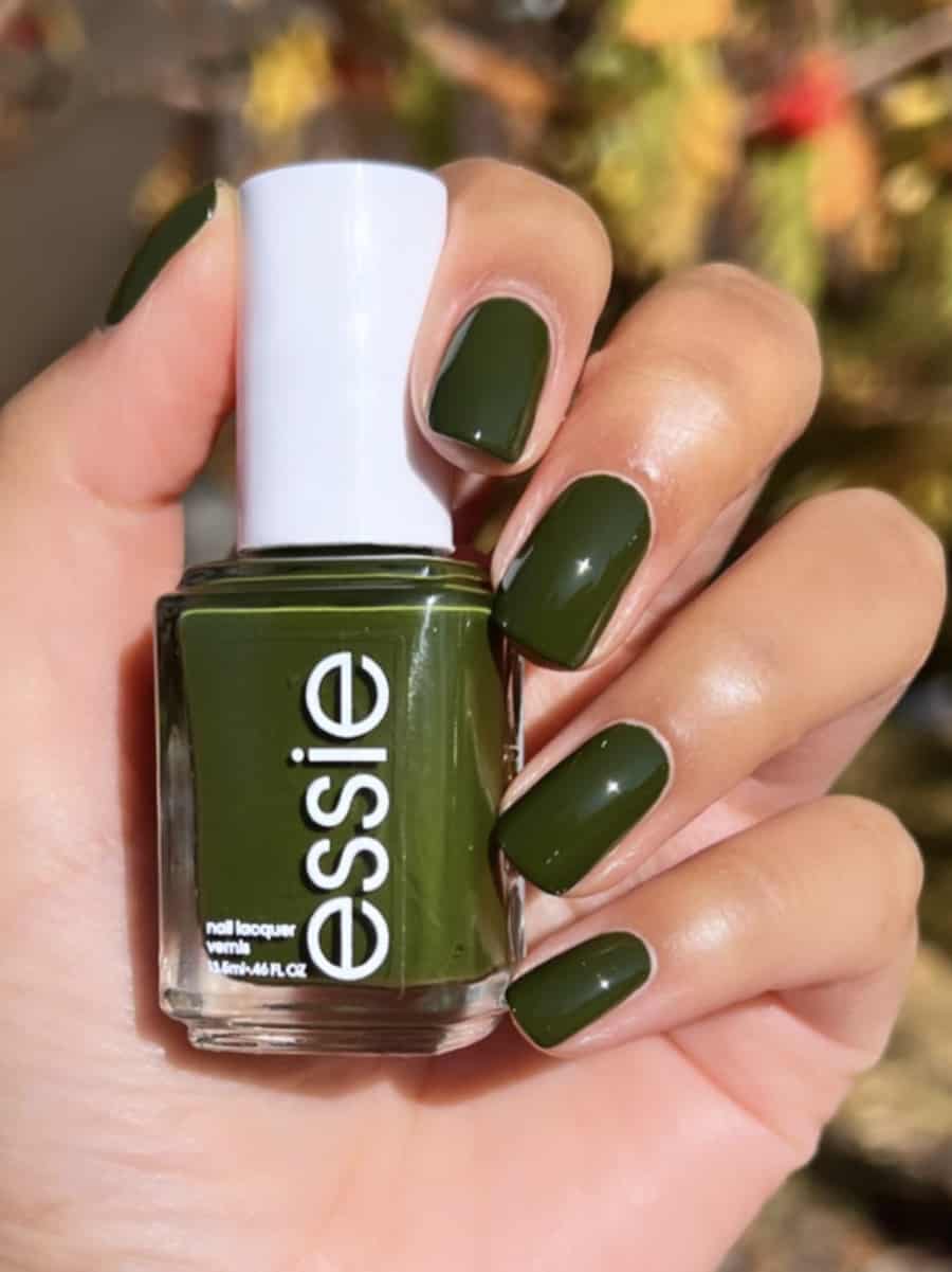 a hand with short square nails painted in an earthy forest green shade