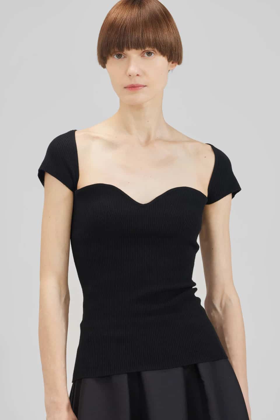 woman wearing a black ribbed sweetheart neckline short-sleeved top in black that is a dupe of the Khaite Ista top 