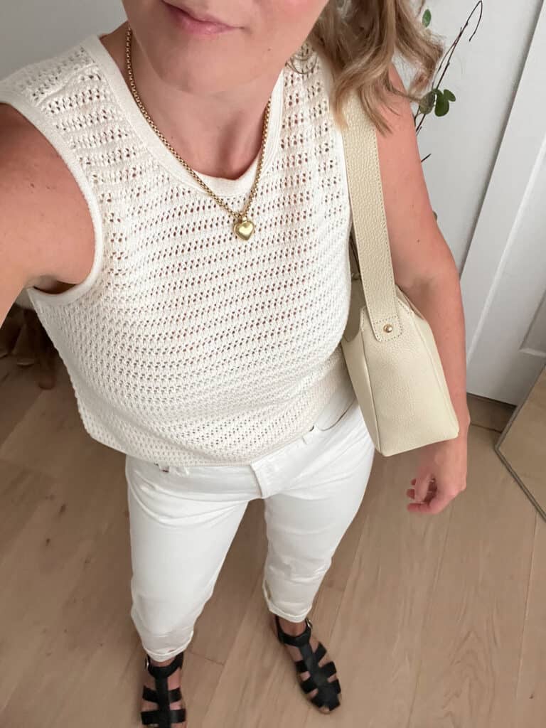 woman wearing an ivory crochet knit tank with off-white jeans and black Poppy Barley fisherman sandals